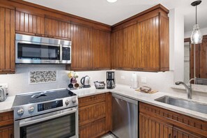 A kitchen with wooden cabinets, stainless steel appliances, and a white tiled backsplash.