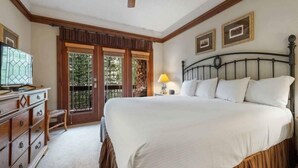 A bedroom with a large bed, wooden headboard, a dresser, a desk, a lamp, and a ceiling fan. - Charming 2BR Condo at The Charter A330 with Updated Kitchen & Fireplace! (Beaver Creek)