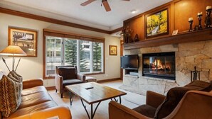 A cozy living room with a fireplace, leather sofas, a coffee table, and a television. - Charming 2BR Condo at The Charter A330 with Updated Kitchen & Fireplace! (Beaver Creek)