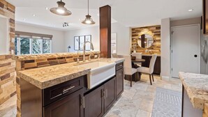 A modern kitchen with granite countertops, dark cabinetry, and pendant lighting. - The Charter at Beaver Creek A360 (Beaver Creek)