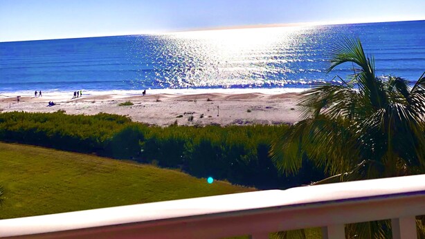 A beach with a clear sky and the sun shining on the water. - Luxurious unit. Sleeps 4. 1.1/2 baths. Beach steps away! (Fort Myers Beach)