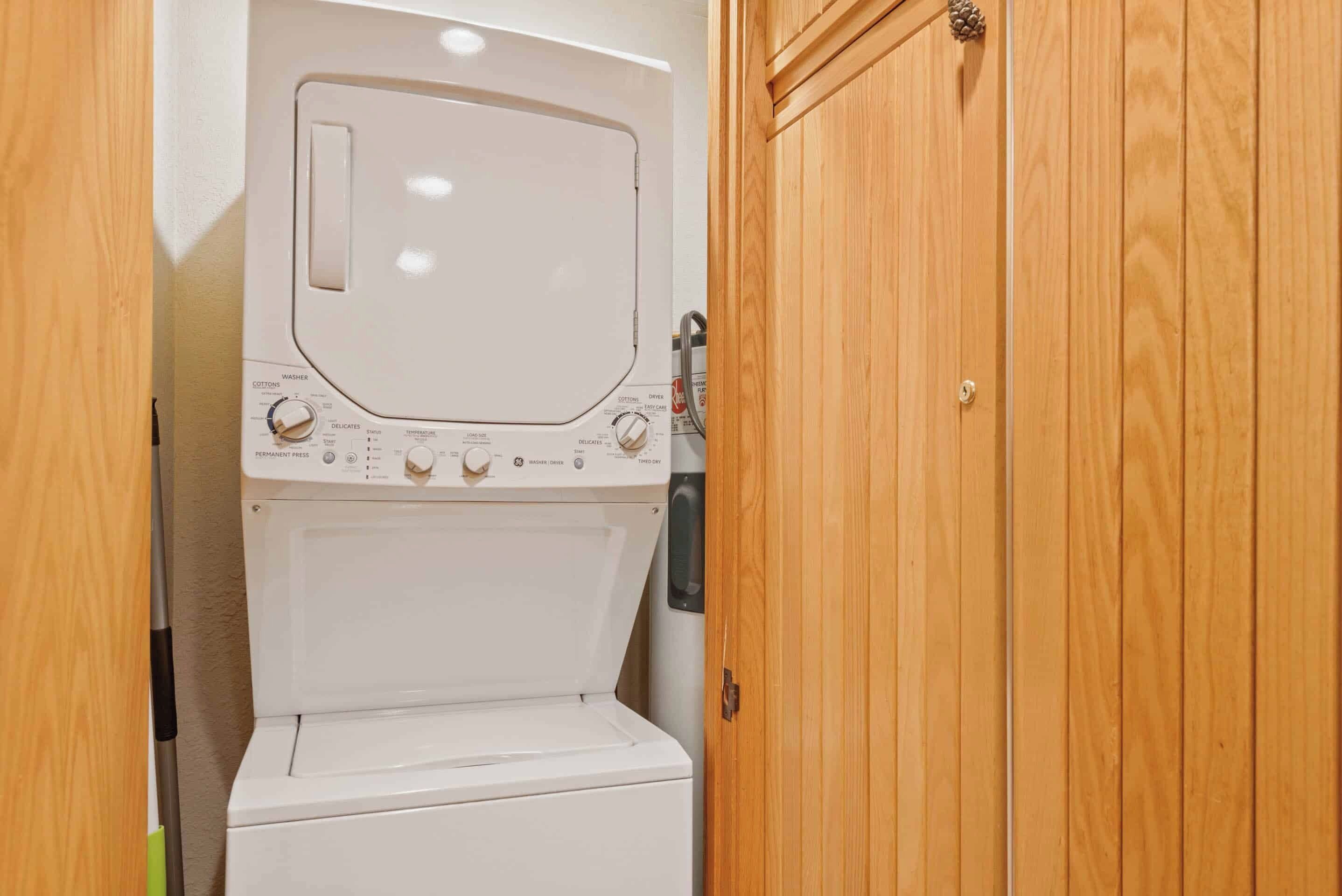 A compact, white washer and dryer unit with a control panel featuring multiple settings and a permanent press option.
