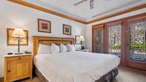 Ein Schlafzimmer mit einem großen Bett, einem Holzkopfteil, zwei Nachttischlampen, einem Nachttisch und einem Deckenventilator.