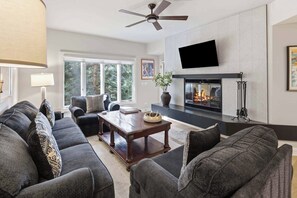 A modern living room with a fireplace, comfortable seating, and a television mounted on the wall.