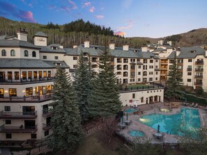 A resort with multiple buildings, a swimming pool, and surrounding trees. - The Charter at Beaver Creek E435 (Beaver Creek)