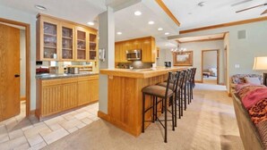 Una cocina moderna con armarios de madera, una isla central con taburetes de bar y un microondas.