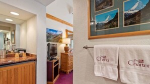 Une chambre d’hôtel avec un comptoir en bois, une télévision, une lampe et un cadre photo fixé au mur, contenant plusieurs images.