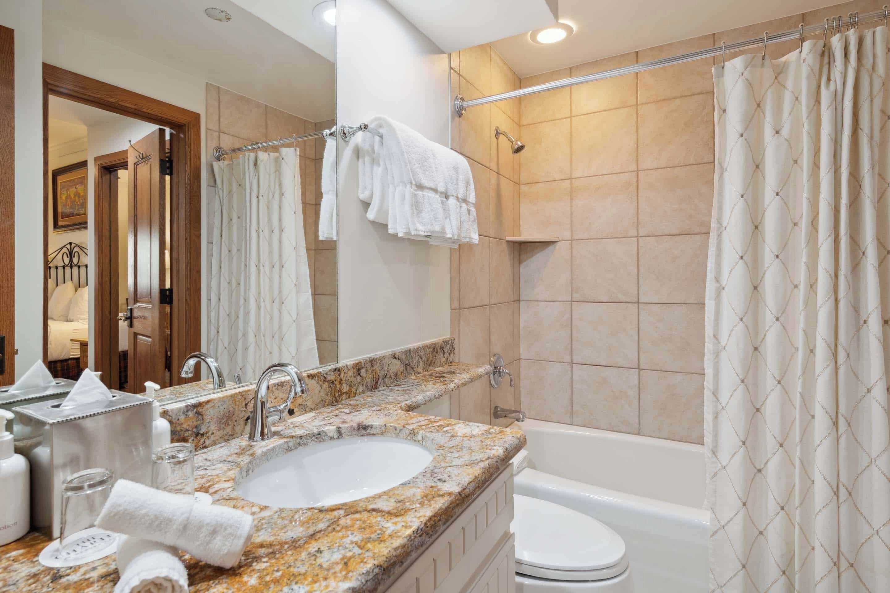 A bathroom with a sink, mirror, and a shower curtain.