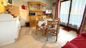 Un espace de vie compact comprenant un coin repas, une kitchenette et un téléviseur.