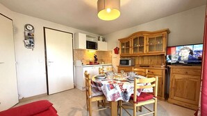 Une cuisine compacte avec un coin repas, des meubles en bois, un four à micro-ondes et un téléviseur.
