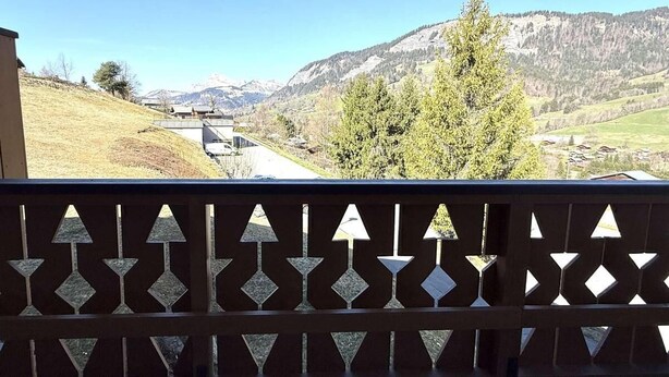 Un balcon offrant une vue sur un paysage montagneux, une route et un bâtiment situé au loin.