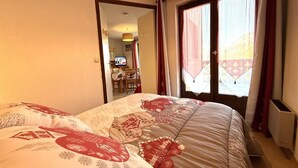 Une chambre avec un grand lit, une fenêtre avec des rideaux et un téléviseur visible au fond.