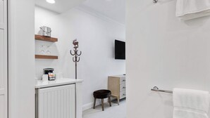 A modern bathroom with a white radiator, a wooden shelf with a kettle, a coffee maker, and a black stool. - The Charter at Beaver Creek E135 (Beaver Creek)