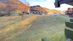 A residential area with a grassy lawn, a tree, and a building with multiple balconies.