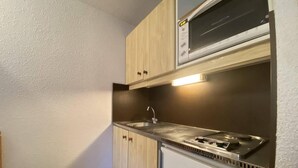 A compact kitchen with a microwave, stove, sink, and a small refrigerator.
