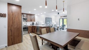 A modern kitchen with wooden cabinets, stainless steel appliances, and a dining area with a wooden table and chairs. - The Charter at Beaver Creek E130 (Beaver Creek)