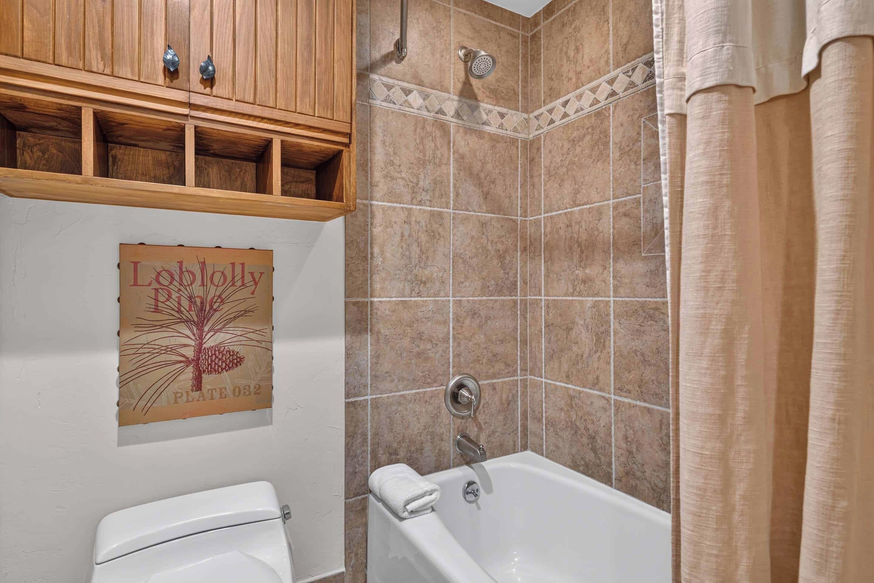 A bathroom with a bathtub, a toilet, and a shower area.