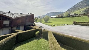 A rural road with houses on either side, a clear sky, and mountains in the background.