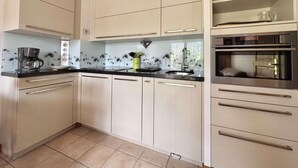 A kitchen with light-colored cabinets, a black countertop, and a built-in microwave.