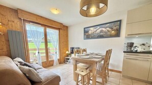 A cozy living room with a sofa, a dining table set for four, and a kitchen area with cabinets and a stove.