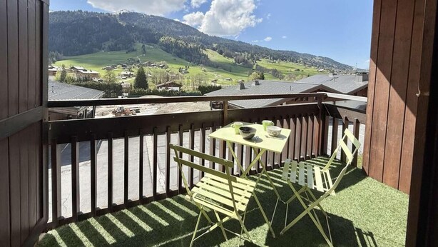 A balcony with a table and chairs, a view of a green valley and mountains, and a wooden railing. - 300m from resort center, 1st floor, view ski slopes, balcony, parking, tv, ski locker, 35m² (Praz-sur-Arly)