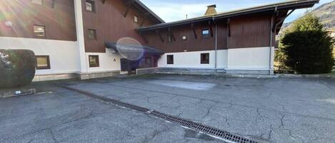 A building with a flat roof, a large open paved area, and a drainage grate.