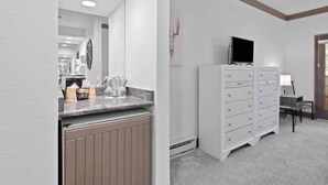 Ein modernes Badezimmer mit Waschtisch, Spiegel, Fernseher auf einem Schrank und Heizkörper.
