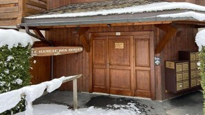Un chalet en bois dont l’entrée est recouverte de neige, et sur lequel on peut lire l’inscription « Le Hameau des Neiges ».