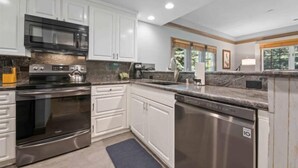 A modern kitchen with white cabinets, stainless steel appliances, granite countertops, and a dishwasher.