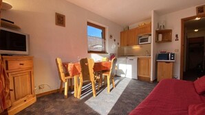 A compact room with a dining table and chairs, a bed, a kitchenette, and a window. - 1st floor, balcony, parking, tv, ski locker, 25m², Praz sur Arly (Praz-sur-Arly)