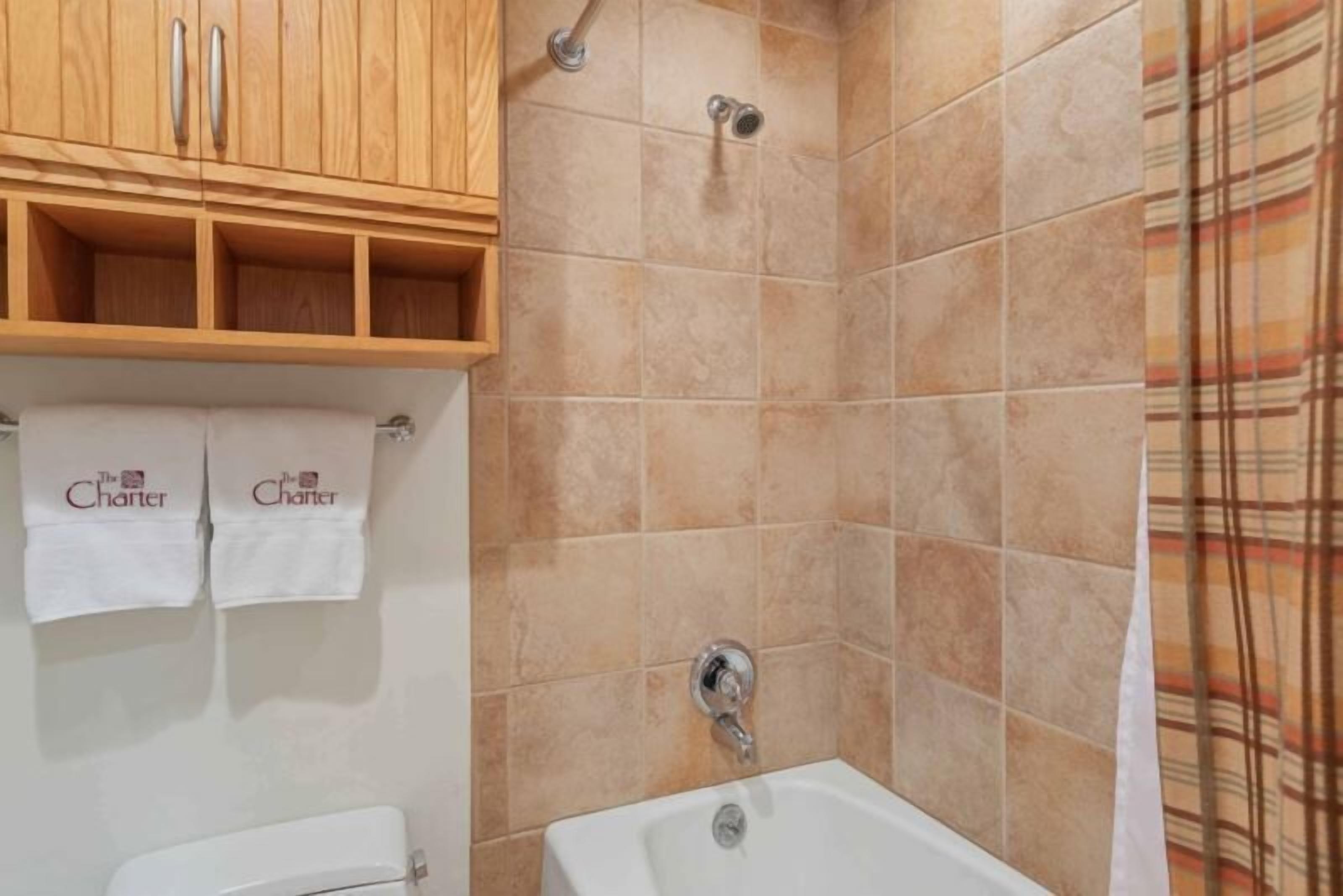 A bathroom with a bathtub, a shower, and wooden cabinets above the sink.