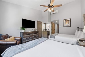 A modern bedroom with a bed, a desk, a chair, a ceiling fan, and a television. - The Charter at Beaver Creek D455 (Beaver Creek)