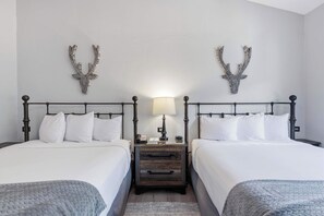 Une chambre d’hôtel avec deux lits, une table de chevet avec une lampe et des bois de cerf accrochés au mur.