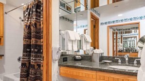 Een badkamer met een douche, een wastafel, een spiegel en een handdoekhouder.