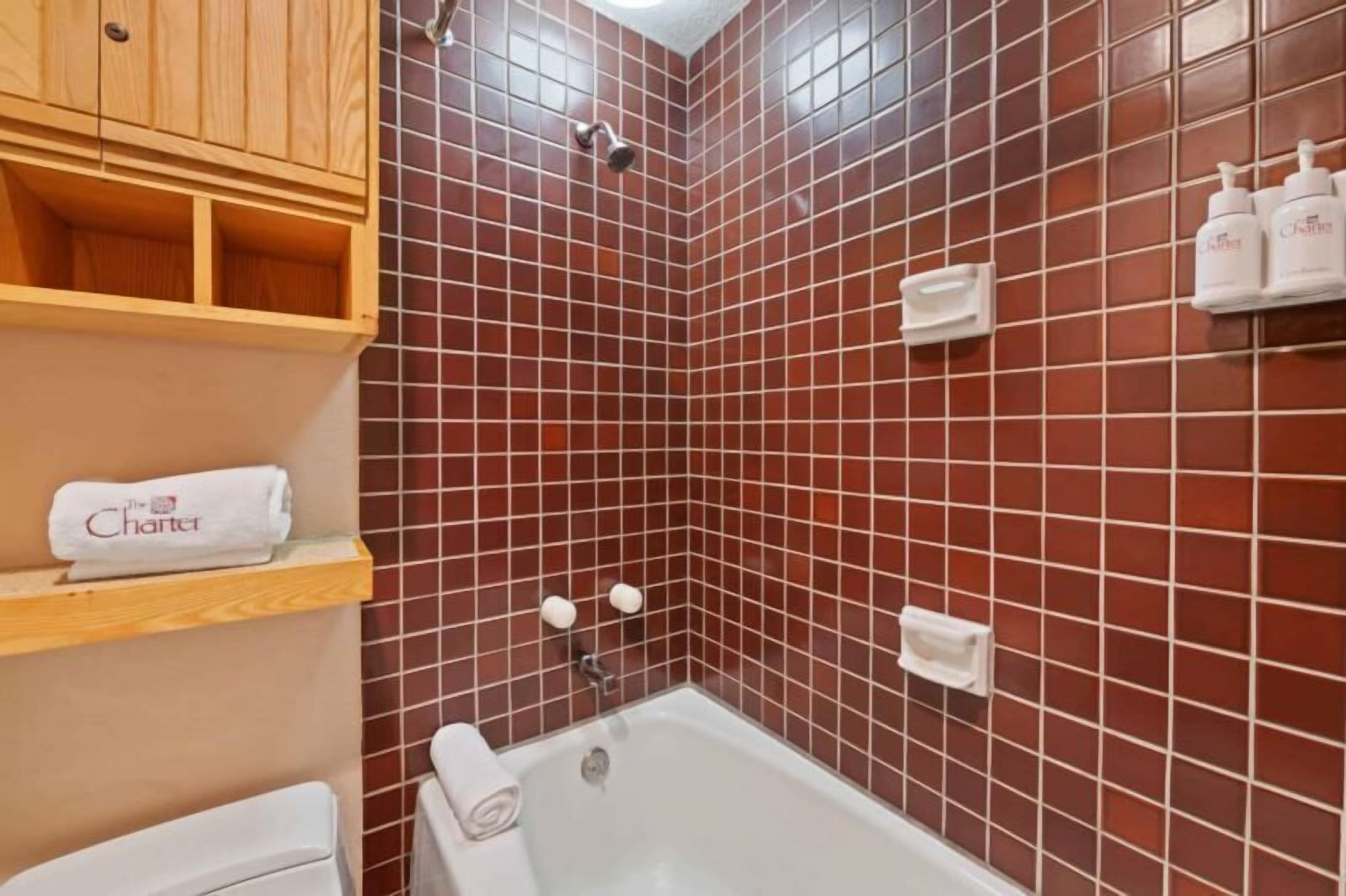 Ein Badezimmer mit einer Badewanne, einem Holzschrank und roten Fliesenwänden.