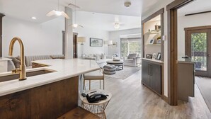 A modern kitchen with a central island, a dining area with a sofa and chairs, and a living room with a couch and a coffee table.