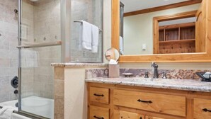 A bathroom with a glass-enclosed shower, a bathtub, wooden cabinets, and a marble countertop. - The Charter at Beaver Creek D255 (Beaver Creek)
