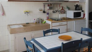Cucina con mobili bianchi, microonde, lavello e tavolo da pranzo con sedie.