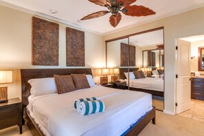 Une chambre d’hôtel avec un grand lit, deux tables de chevet, un ventilateur de plafond et un grand miroir.