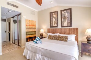 Ein Hotelzimmer mit einem großen Bett, einem Wandbild und einer Tür zu einem anderen Raum.