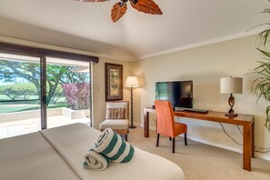 Una habitación de hotel con una cama, un escritorio con televisor, una silla, una lámpara y vistas a un jardín.