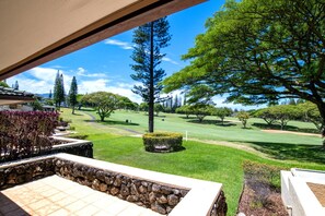 Blick auf einen Golfplatz mit einer Steinmauer und einer Terrasse im Vordergrund.