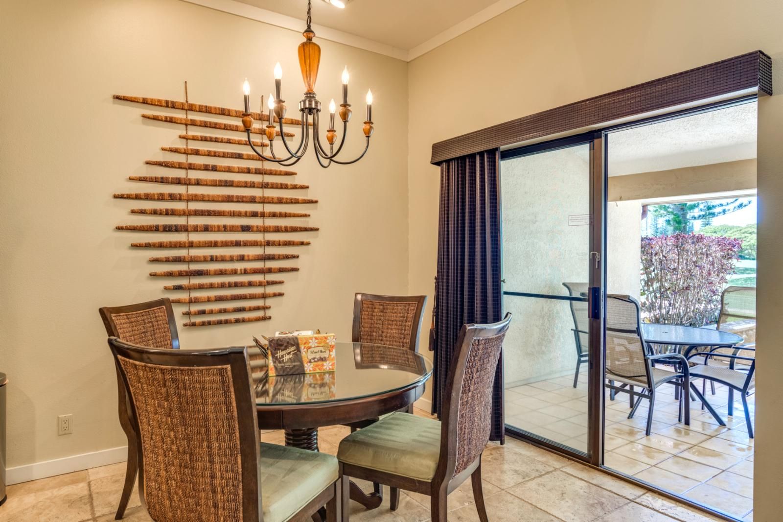 A dining area with a round table, four chairs, a chandelier, and a decorative wall piece.