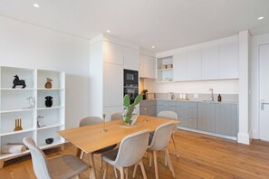 Una cocina moderna con armarios blancos, una mesa de comedor de madera y sillas.