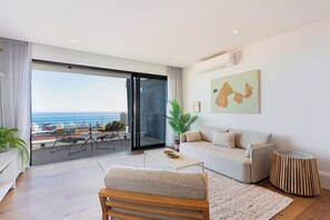 A modern living room with a large sliding glass door leading to a balcony with a city view.