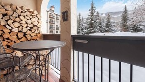 Ein Balkon mit Holzstapel, Tisch und Stühlen.