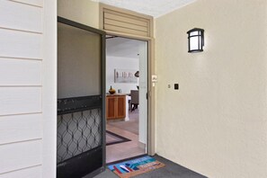 Un couloir avec une porte donnant sur un espace cuisine.