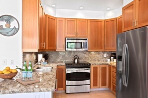 A kitchen with wooden cabinets, stainless steel appliances, granite countertops, and a sink.