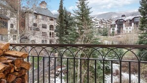 En bergsort med traditionell arkitektur, ett snötäckt landskap och en stor hög med ved.