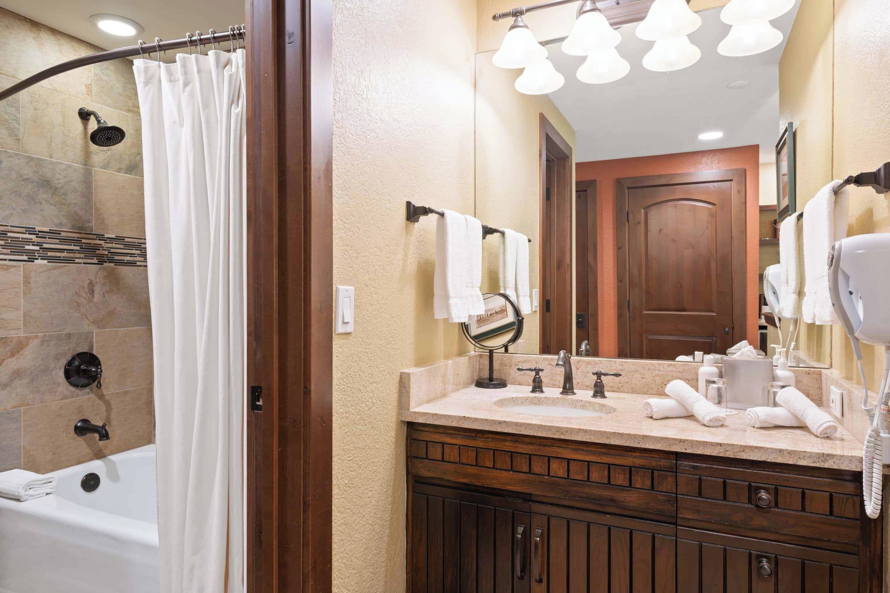 A bathroom with a bathtub, a vanity with a mirror, and a hairdryer.